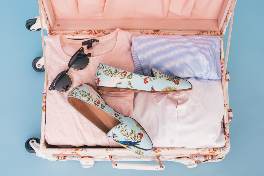 valise avec vêtements lunettes de soleil et chaussures femme